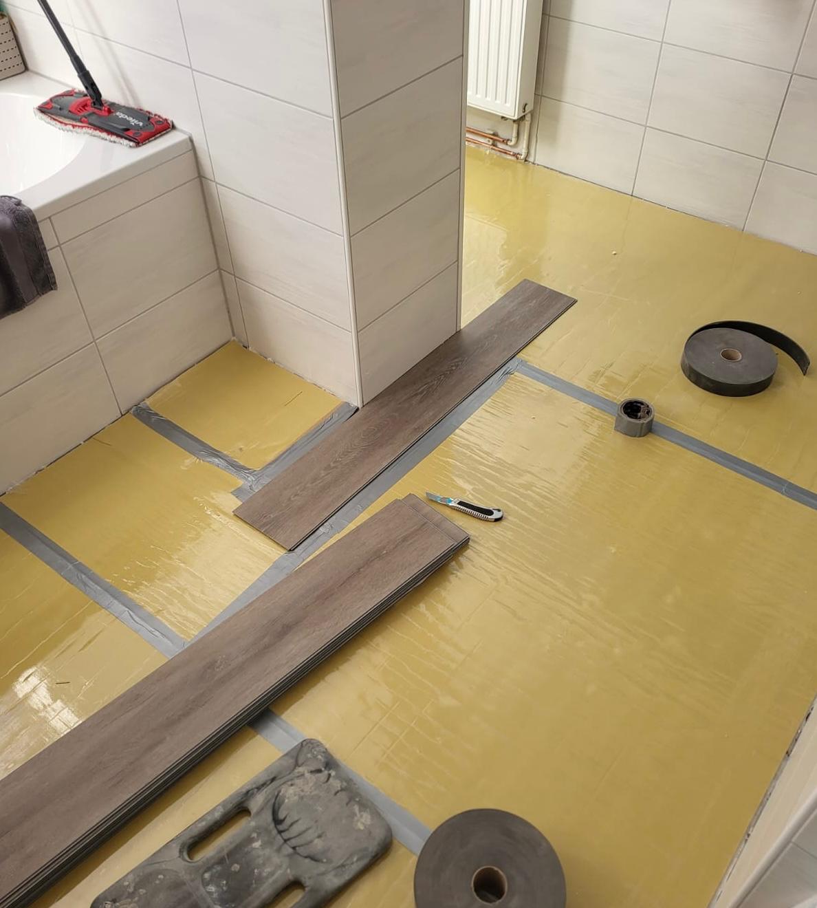 Trittschaldämmung Bodenverlegung mit grauen Fliesen und braunen Holzplanken in einem Raum.