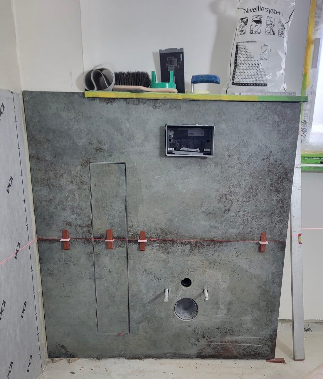 Toilettenelement Betonwand mit Installationsöffnung und Werkzeugen an der Oberkante.