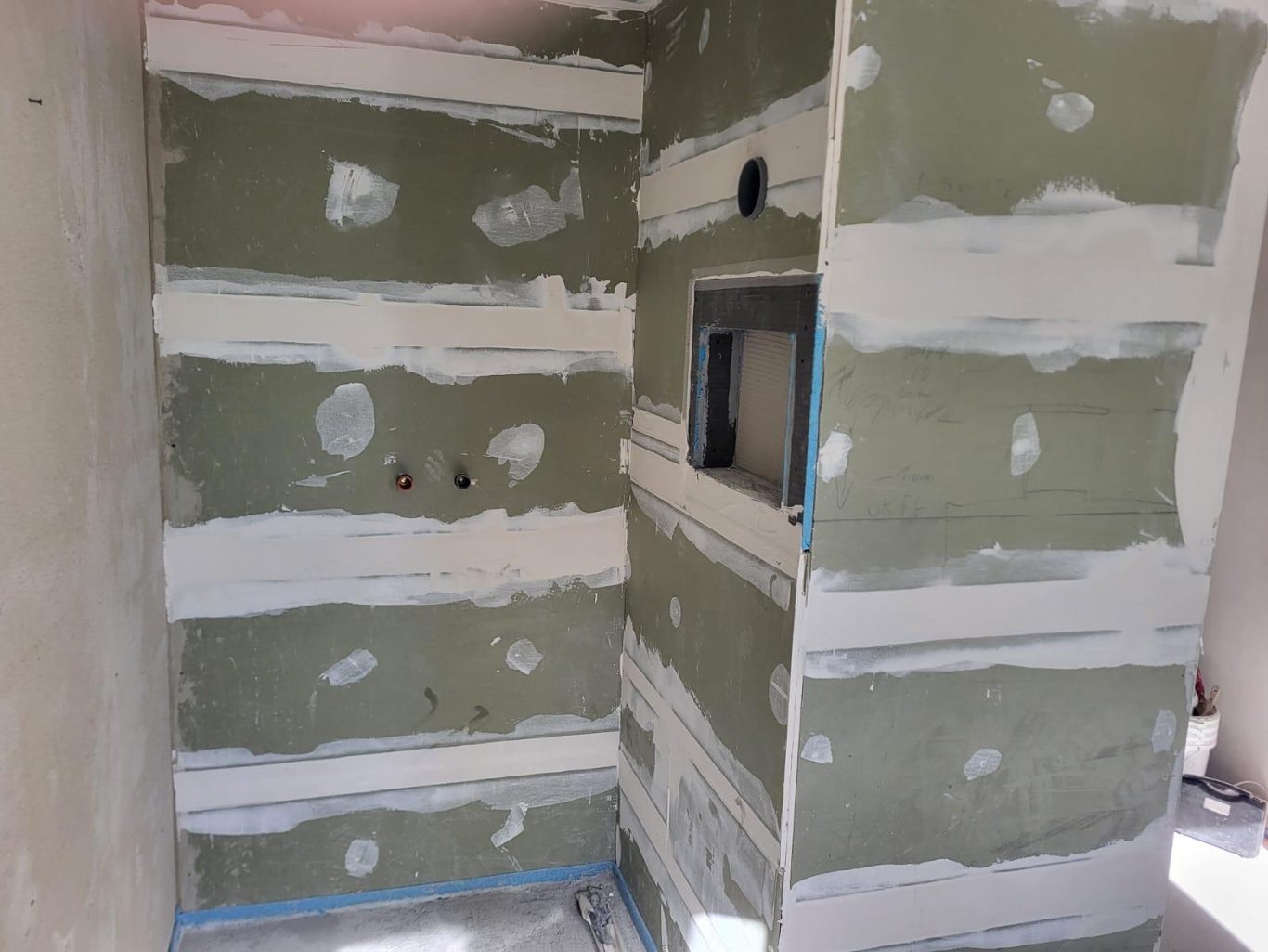 Trockenbau Dusche Wände mit glattem Putz, grün und weiß gestreift, teilweise mit Aussparungen.