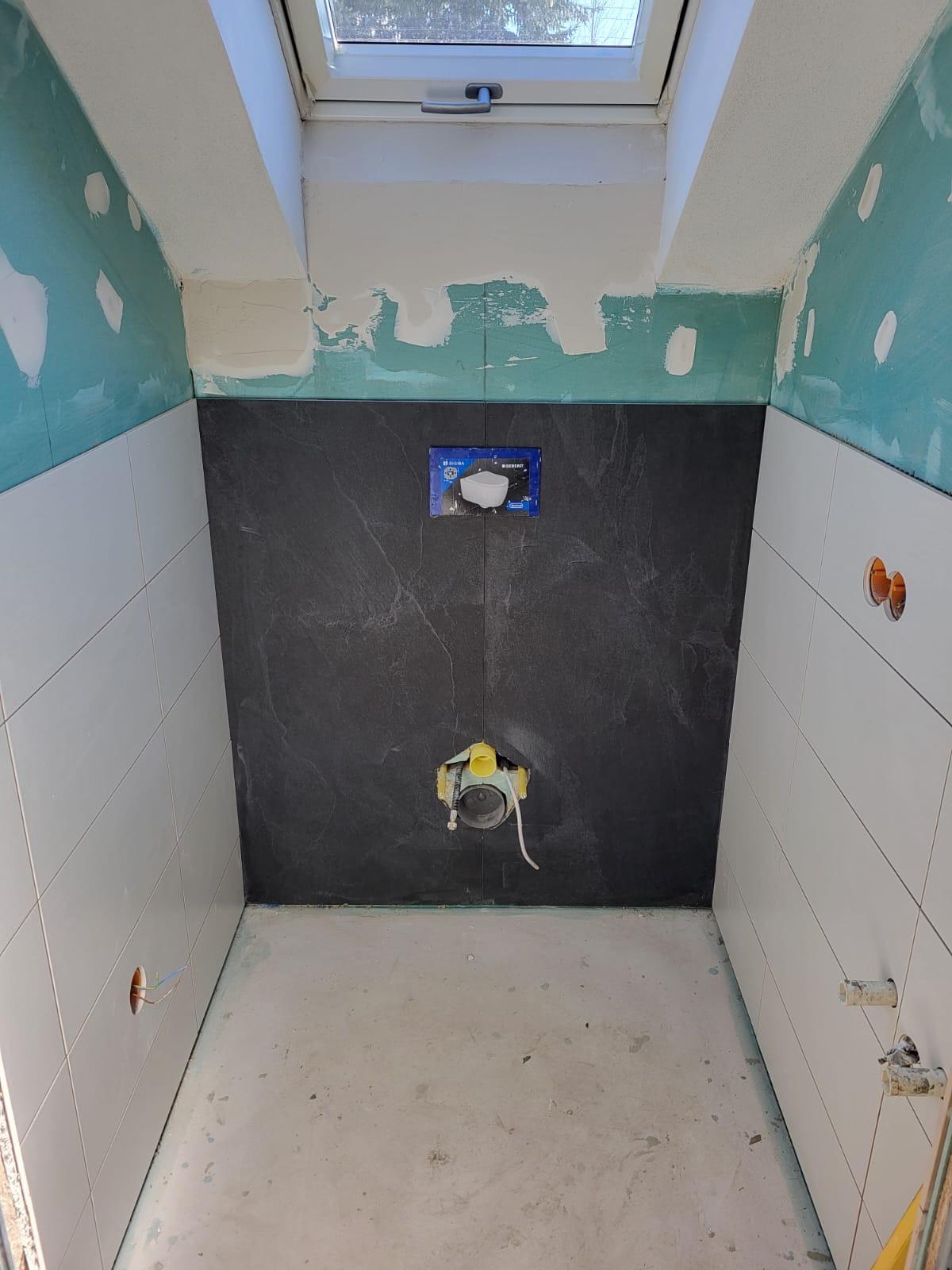 Wandfliesen Leerer Raum mit halb verputzten Wänden und einem schwarzen Fliesenbereich.