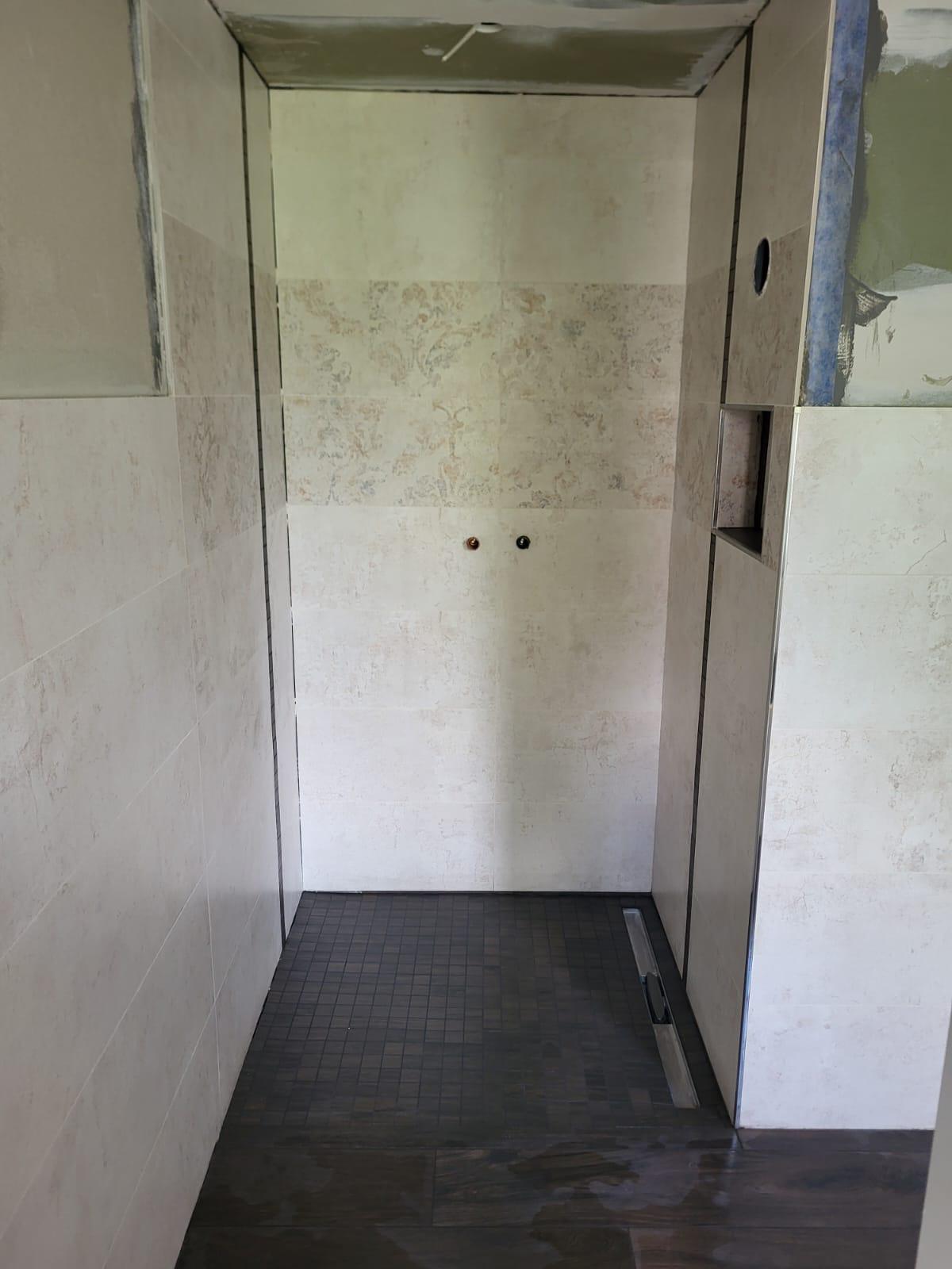 Dusche Neubau Leere, unrenovierte Liftkabine mit grauen Wänden und dunklem Boden.