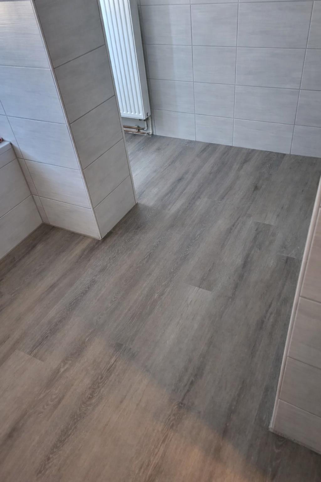 Vinylboden Holzbodenbelag in einem modernen Raum mit weißen Wänden und einem Heizkörper.